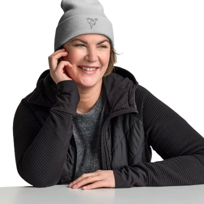 A woman sits at a table while wearing a grey custom cuffed beanie. Custom cuffed beanies are available at custom custom clothing.